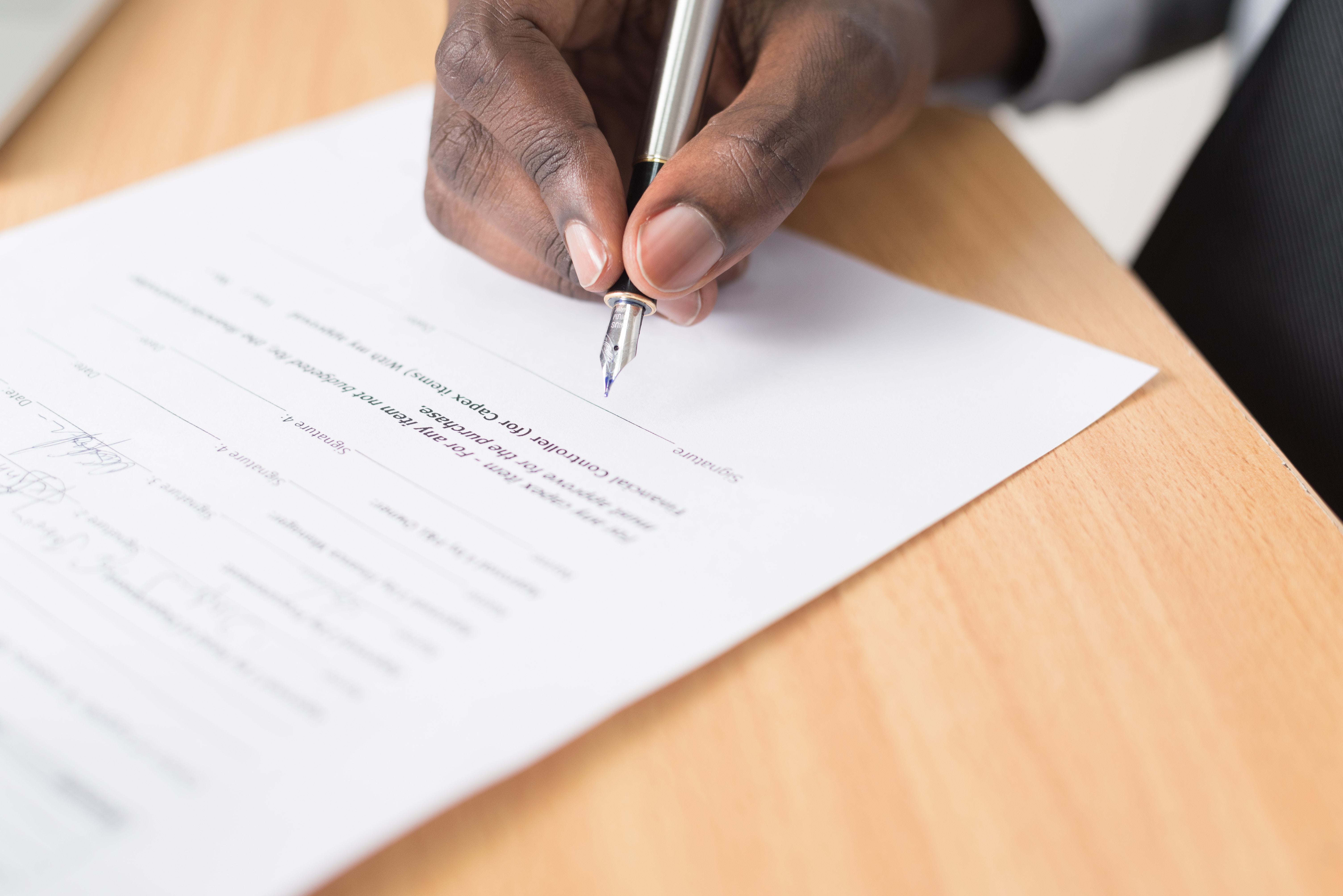 "A close-up of a form and someone about to sign it."