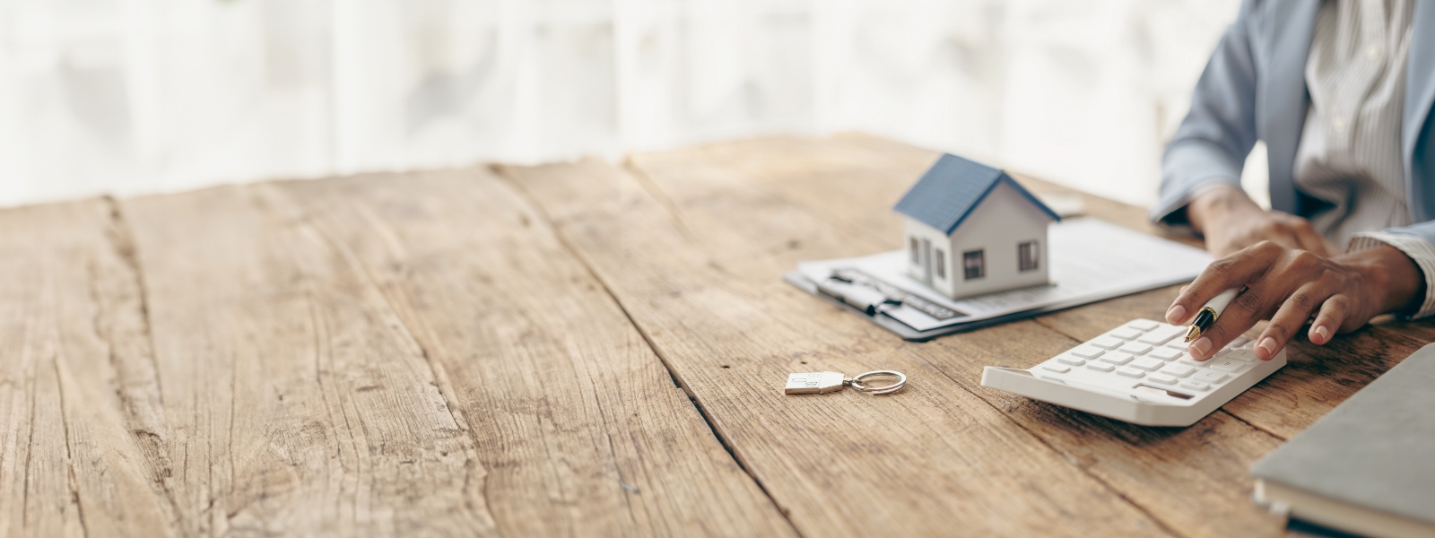 A model of a house on a table in front of a person.