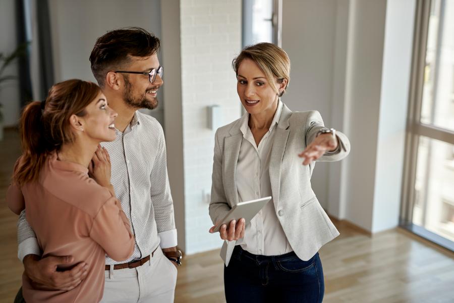 real estate agent speaking to clients, showing a house